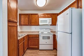 Corona apartment for rent - a kitchen with brown cabinets and white appliances