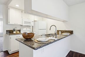 Huntington Beach apartment for rent - A kitchen with a granite countertop and white cabinets.