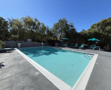 Alhambra apartment for rent - A large outdoor swimming pool surrounded by trees and lounge chairs.