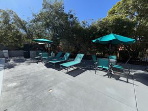 Alhambra apartment for rent - A sunny day at the outdoor seating area with green chairs and umbrellas.