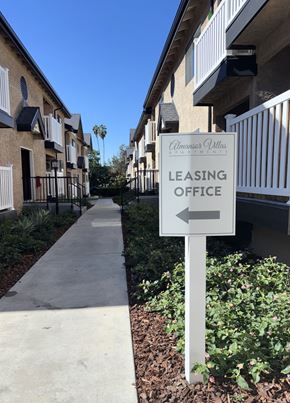 Alhambra apartment for rent - A sign for a leasing office is on the right side of a walkway.