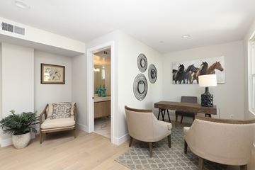 Pomona apartment for rent - A living room with a chair, a table, and a painting on the wall.