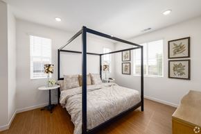 Fontana apartment for rent - A bedroom with a four poster bed and a nightstand with a lamp.