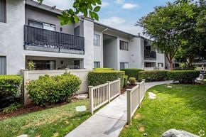 Anaheim apartment for rent - A residential building with a well-maintained lawn and a white picket fence.