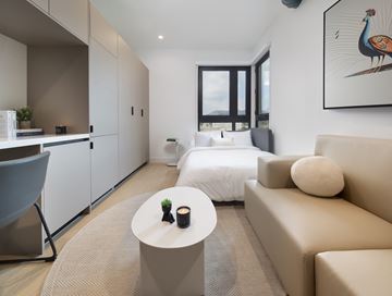 Los Angeles apartment for rent - A modern living room with a grey chair, a white sofa, and a painting of a peacock on the wall.