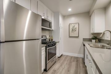 Newport Beach townhouse for rent - A modern kitchen with a stainless steel refrigerator and white cabinets.