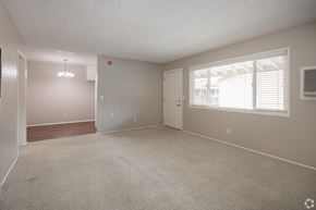 Orange apartment for rent - A spacious room with a carpeted floor and a window with blinds.