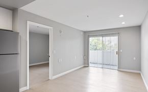 Garden Grove apartment for rent - A spacious, empty room with a refrigerator on the left and a sliding glass door on the right.
