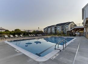 Brewster apartment for rent - a swimming pool with chairs around it in front of an apartment building