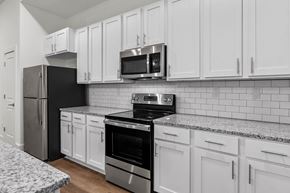 Jackson apartment for rent - A kitchen with white cabinets and black appliances. at The Quarter Lofts Apartments, Mississippi, 39216