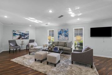 Jackson townhouse for rent - A living room with a grey sofa, a grey armchair, a grey ottoman, a white rug, and a painting on the wall.
