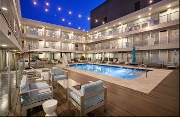 Jackson apartment for rent - A large outdoor pool area with lounge chairs and a hot tub at night.
