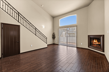 An empty living room with a fireplace and a staircase