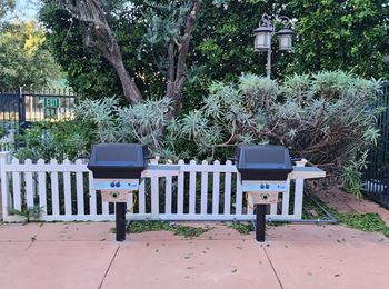 Two parking meters in front of a white fence