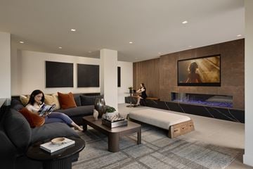Woodland Hills apartment for rent - A woman is sitting on a couch reading a book in a modern living room.