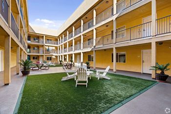 A courtyard with a lawn and chairs and tables