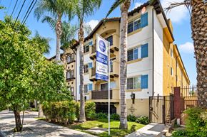 Van Nuys apartment for rent - an apartment building with palm trees and a blue and white street sign
