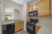 Lake Balboa apartment for rent - a kitchen with wooden cabinets and black appliances at The Village Apartments, Van Nuys, 91406