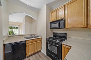 Lake Balboa apartment for rent - a kitchen with wooden cabinets and black appliances at The Village Apartments, Van Nuys, 91406