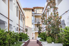 Canoga Park apartment for rent - a city street filled with white apartment buildings and plants at Le Blanc Apartment Homes, Canoga Park
