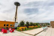 Seattle apartment for rent - A rooftop patio with red chairs and a pool table with the Seattle Space Needle in the background
