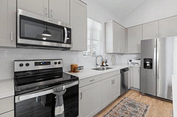A modern kitchen with a stove, microwave, and refrigerator.