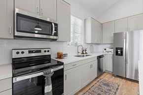 Chandler apartment for rent - a kitchen with stainless steel appliances and white cabinets at Village of Chandler Apartments, Chandler, 85249