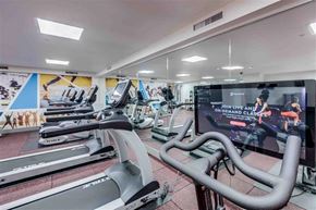 Seattle apartment for rent - A gym with treadmills and a screen showing a live class.