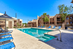 Phoenix apartment for rent - A swimming pool surrounded by blue chairs and a building in the background.
