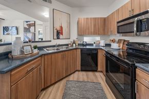 Peoria apartment for rent - A modern kitchen with wooden cabinets and black appliances.