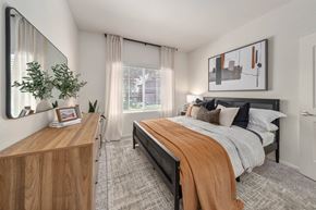 Peoria apartment for rent - A bedroom with a bed, nightstand, and a mirror on the wall.