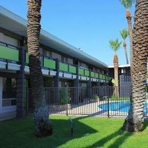 Scottsdale apartment for rent - A building with a pool and palm trees in front.