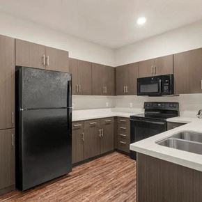 Phoenix apartment for rent - A black refrigerator stands in a kitchen with wooden cabinets and a black oven.