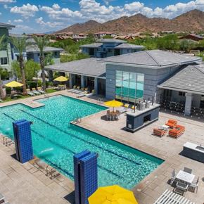 Phoenix apartment for rent - A swimming pool with a yellow umbrella and a building in the background.