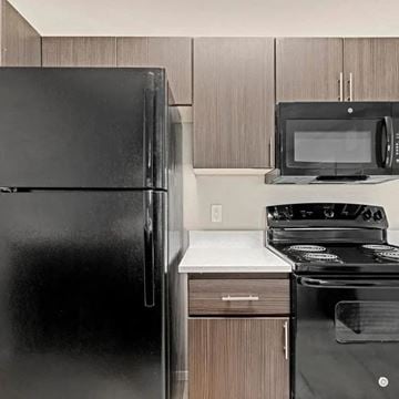 Tucson apartment for rent - A black refrigerator is next to a black microwave and black stove in a kitchen.