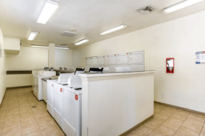 Phoenix apartment for rent - A clean, white-walled laundry room with a row of washers and dryers.