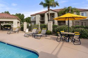 Sun City apartment for rent - A pool area with a table and chairs and a yellow umbrella.