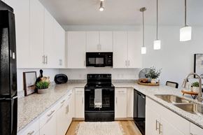 Tucson apartment for rent - A black refrigerator is in a kitchen with white cabinets.