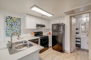 Tucson apartment for rent - A kitchen with a black refrigerator and a sink with a silver faucet.