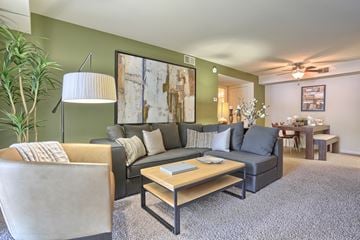Harrisburg apartment for rent - A living room with a grey couch, a wooden coffee table, and a large painting on the wall.