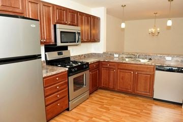 Hummelstown apartment for rent - A kitchen with wooden cabinets and a stainless steel refrigerator.