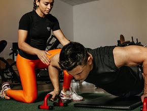 Philadelphia apartment for rent - a young woman spotting while a young man does push ups in a gym