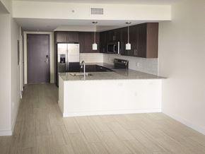 Miami apartment for rent - an empty kitchen with a counter top and a refrigerator at Meridian Point at Goulds Station in Miami, FL, 33170