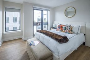 Washington apartment for rent - A bedroom with a large bed and a window overlooking a cityscape.