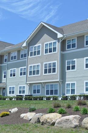 Bourne apartment for rent - a large apartment building with a lawn and rocks in front of it