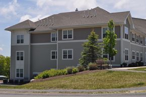 Bourne apartment for rent - a large gray house with a bench in front of it