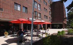 Dover apartment for rent - A man is sitting at a table under a red umbrella in front of a brick building.