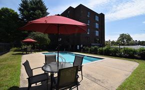 Dover apartment for rent - A red umbrella is on a table next to a pool.