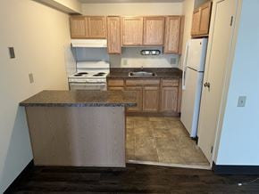 Troy apartment for rent - an empty kitchen with wooden cabinets and a white refrigerator