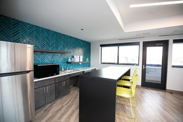 Chicago apartment for rent - A modern kitchen with a black counter and yellow chairs.